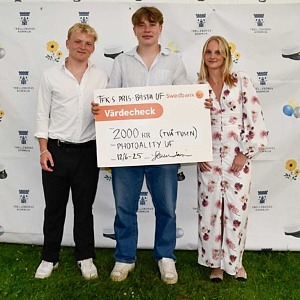 Tre elever som håller upp en värdecheck. 
